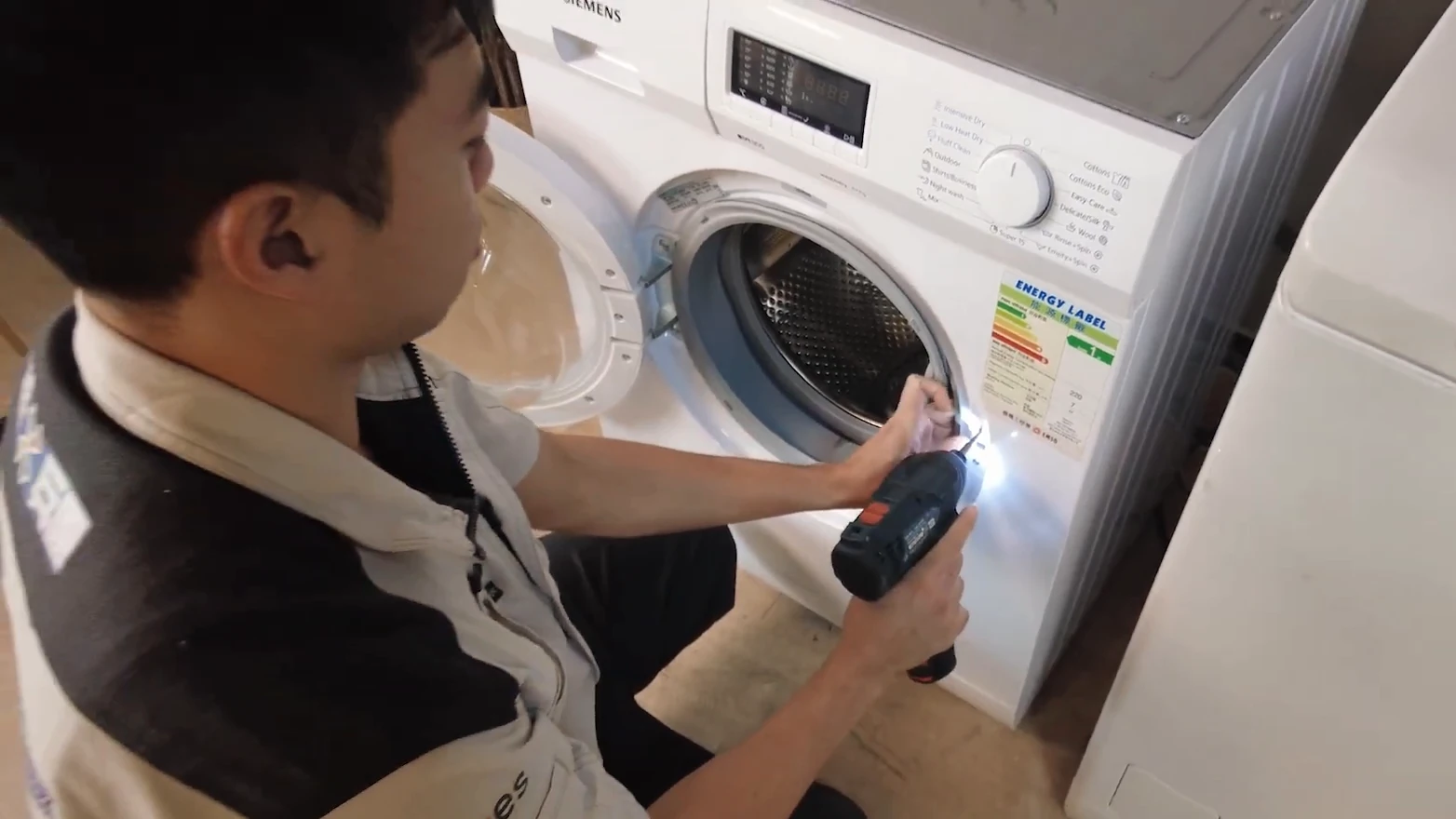 師傅用電鑽處理洗衣機門